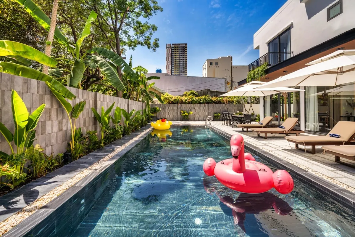 Private villa swimming pool with tropical greenery, shaded loungers and a pink flamingo float